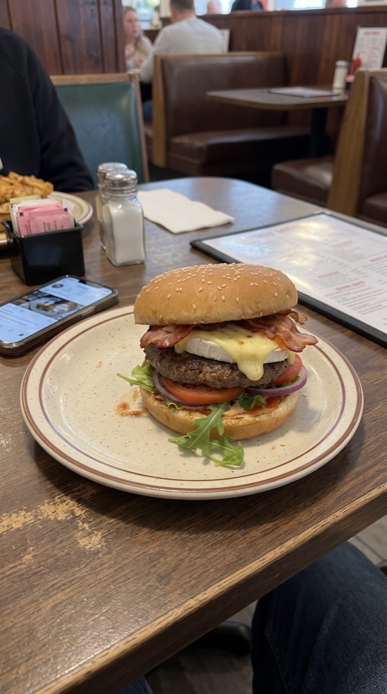 Hamburguesa fotografiada con celular sobre la mesa de un restaurante